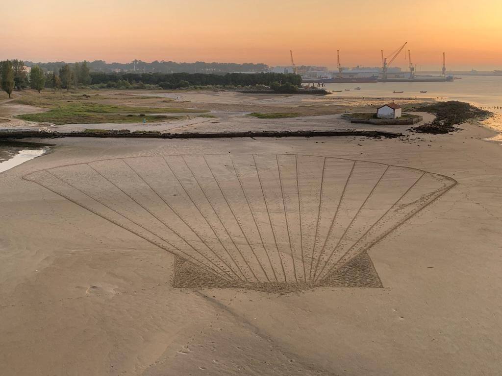 Concha gigante dos Caminhos de Santiago desenhada na areia de praia fluvial de Darque